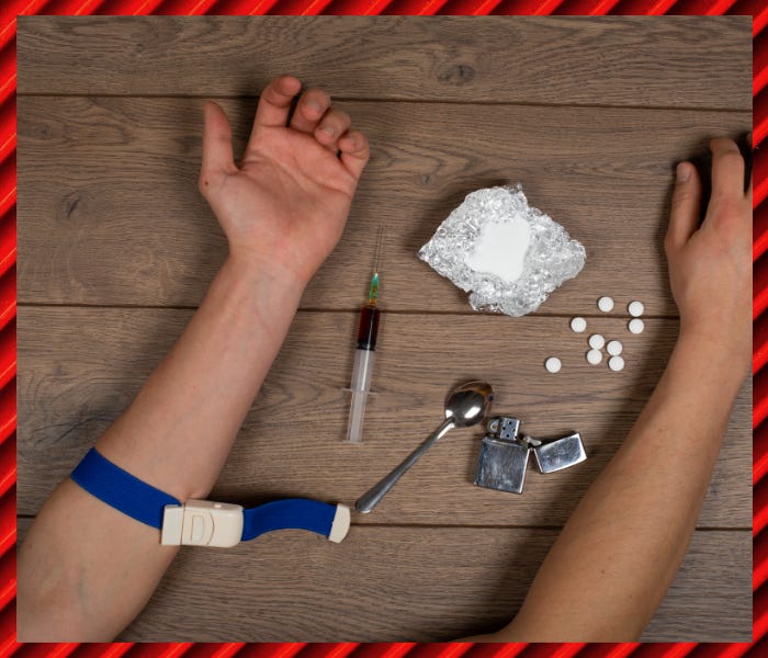 Two arms surrounded with drug paraphernalia