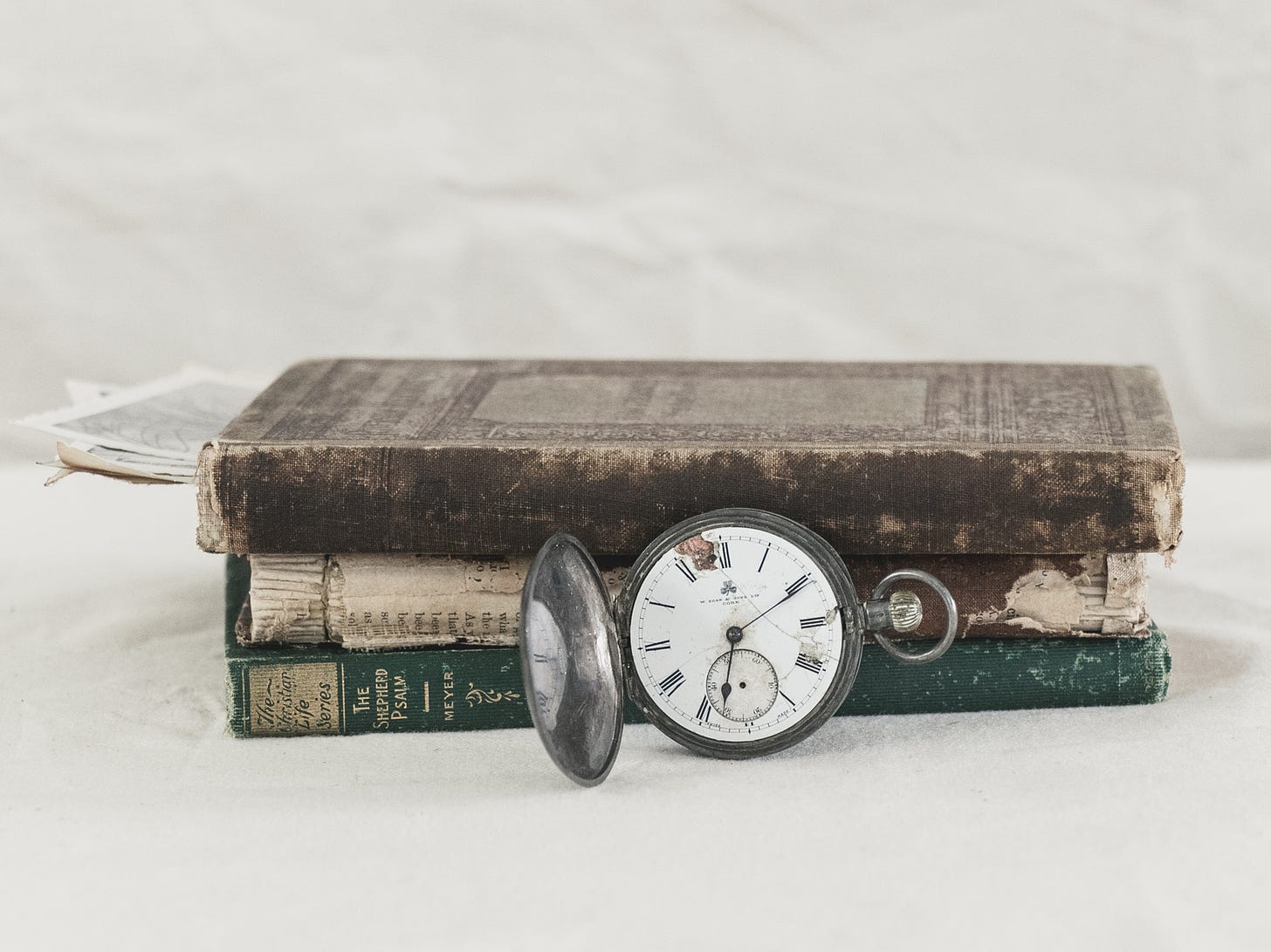 A cracked pocket watch leaning against a stack of old books