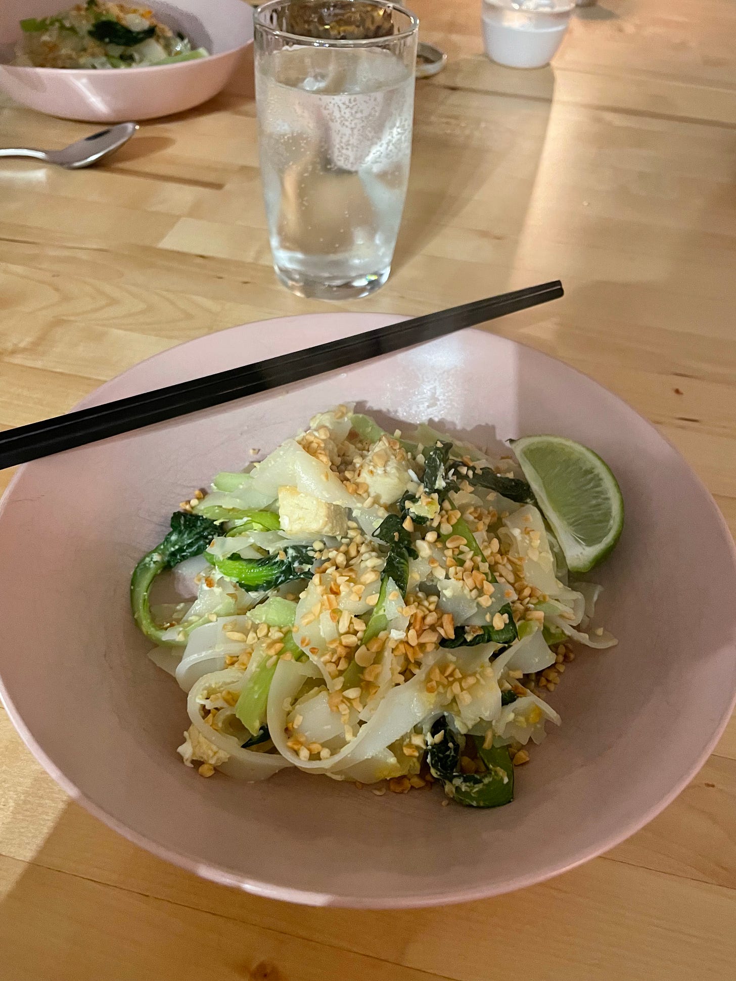 Bowl of pad thai with tofu, topped with crushed peanuts and served with a slice of lime.