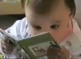 Animated gif of a baby, close-up, zooming in and out as they look at a spread of a small book.