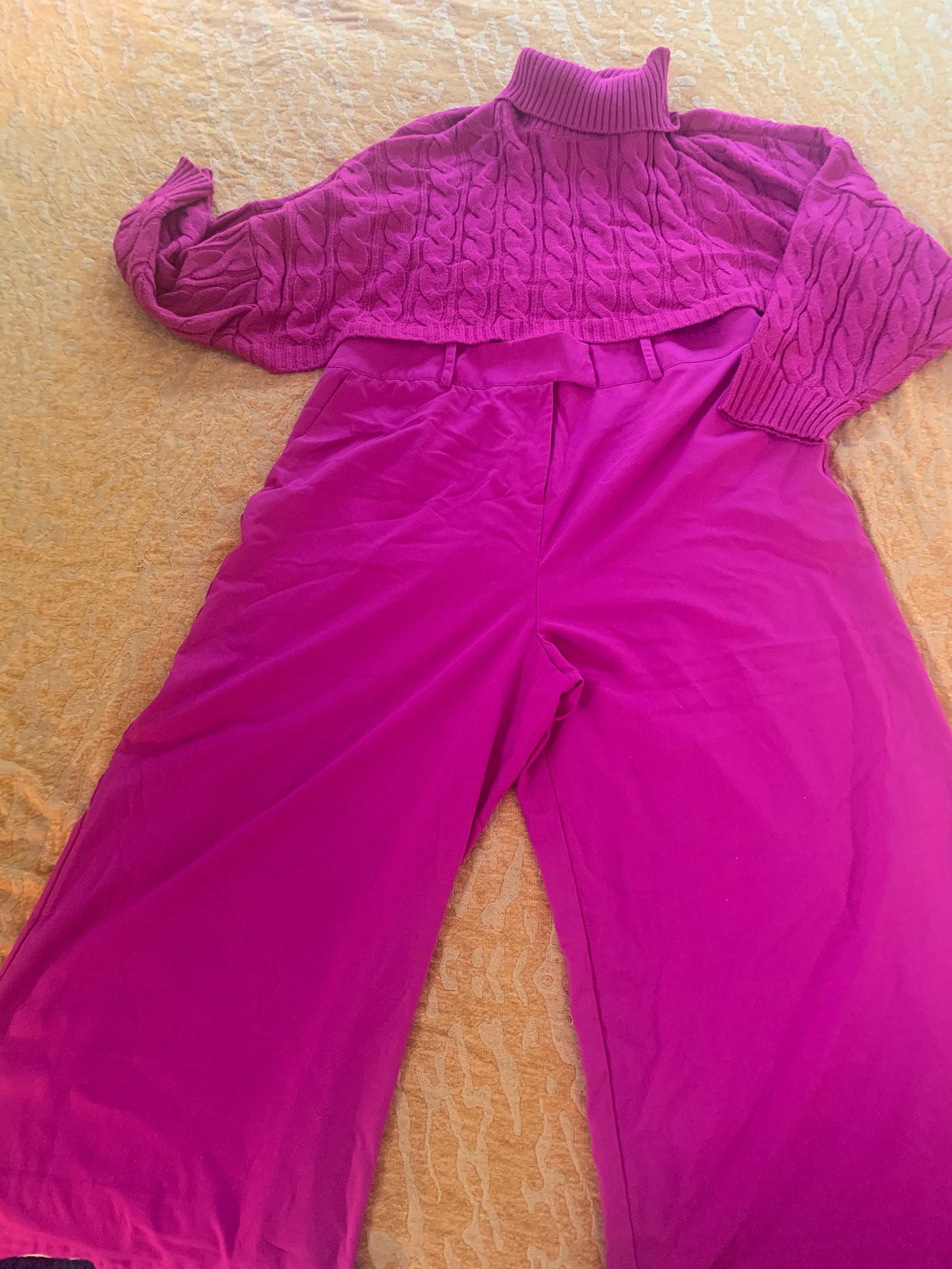 Hot pink turtleneck sweater, hot pink wide legged pants laid out on Caissie's bedspread