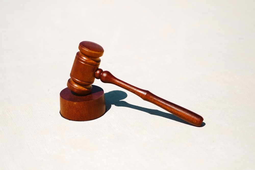 A brown wodden judges gavel with a white background