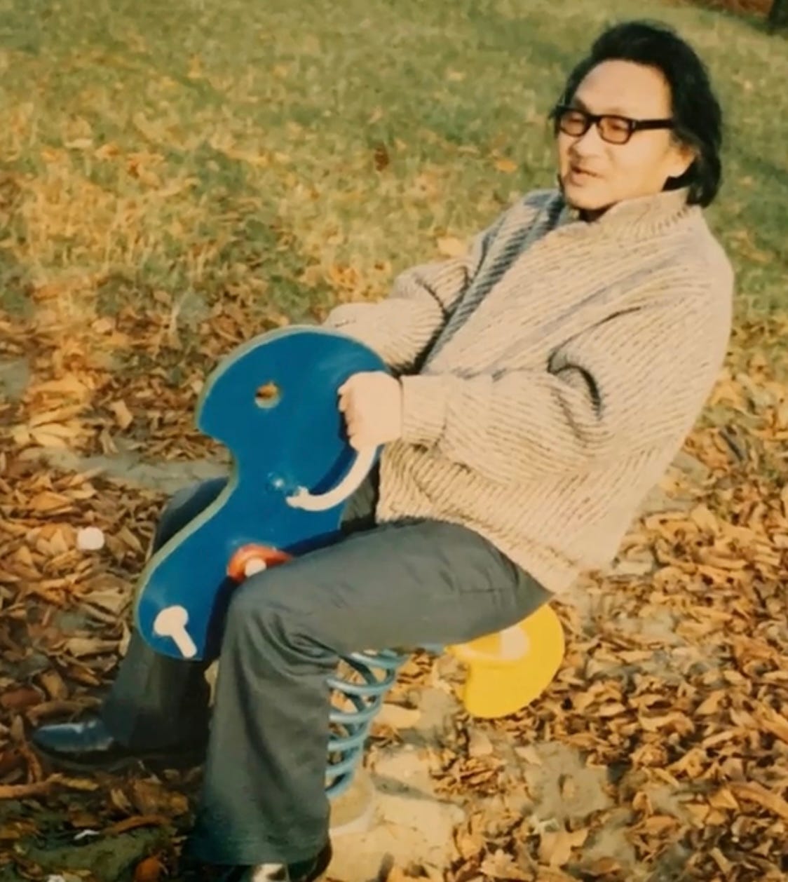 A middle-aged Wang Lisan rides a playground rocking horse in autumn after the end of China's Cultural Revolution