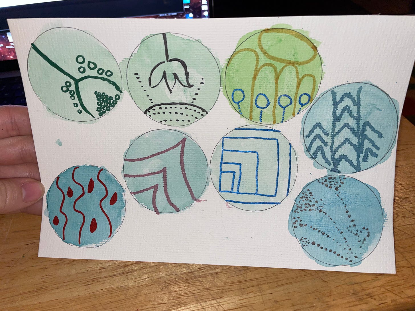 A piece of paper with 8 circles with various shades of greens or blues and different marks on top of them