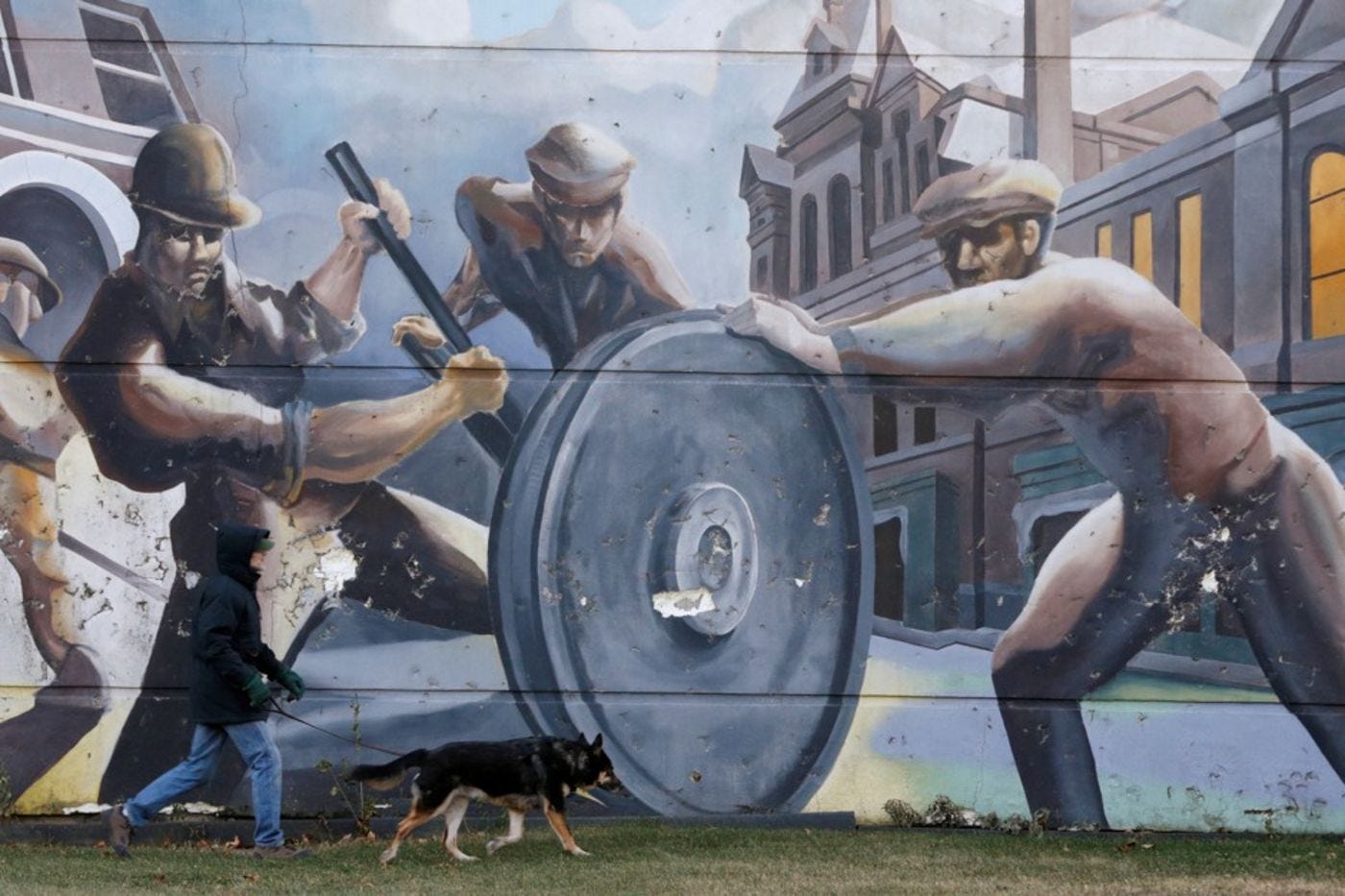 A man walks past a mural of factory workers shoveling coal in Chicago's historic Pullman neighborhood. The Pullman porters, who were paid less than white workers in the town, organized the first African American union.