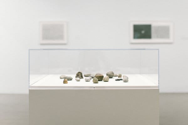 A sculpture of small stones and their painted bronze copies, “To Fix the Image in Memory I-XI” from 1977-1982. Behind it, from left, two drawings, “Untitled (Medium Desert),” from 1974-1975; and “Untitled (Galaxy-Desert),” from  1974.