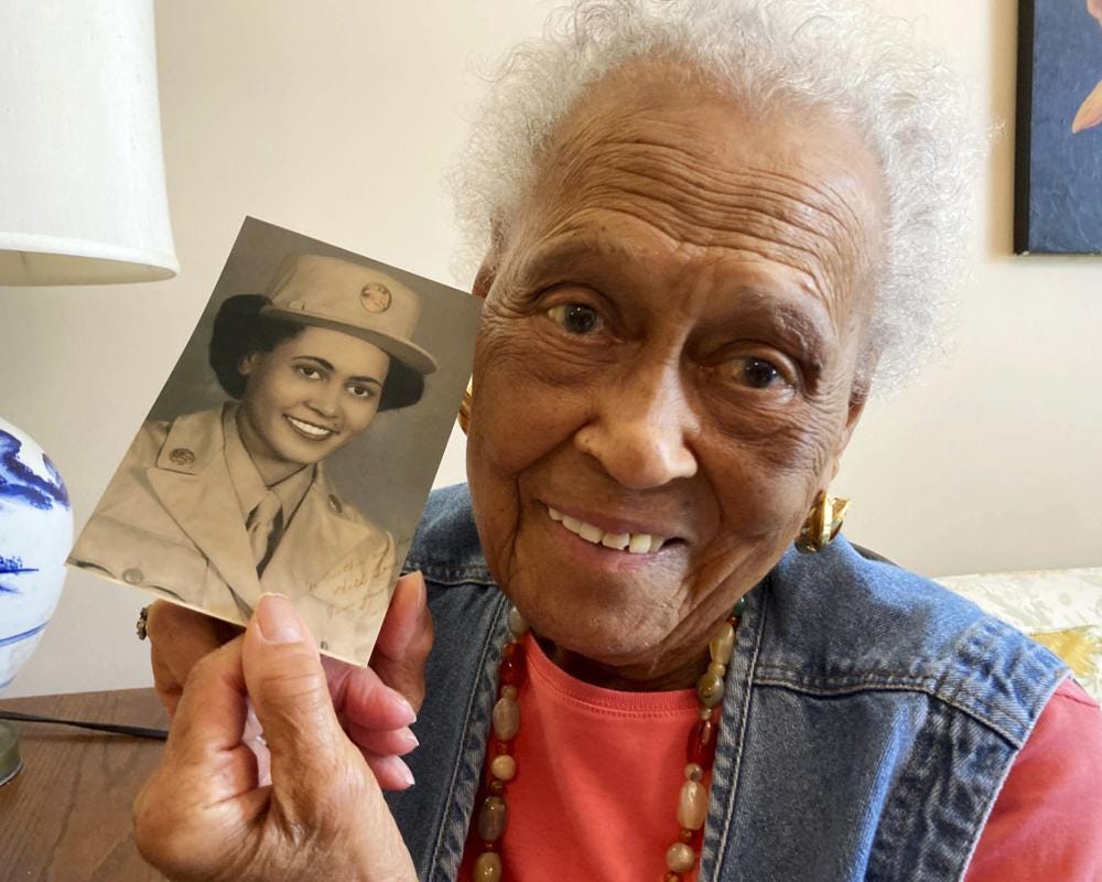 Romay Davis, 102, poses with a photo showing her during World War II, at her home in Montgomery, Ala., Monday, July 25, 2022. Davis is being honored for her service with the all-female, all-Black 6888th Central Postal Directory Battalion, which got mail to U.S. troops in Europe during the war. (AP Photo/Jay Reeves)