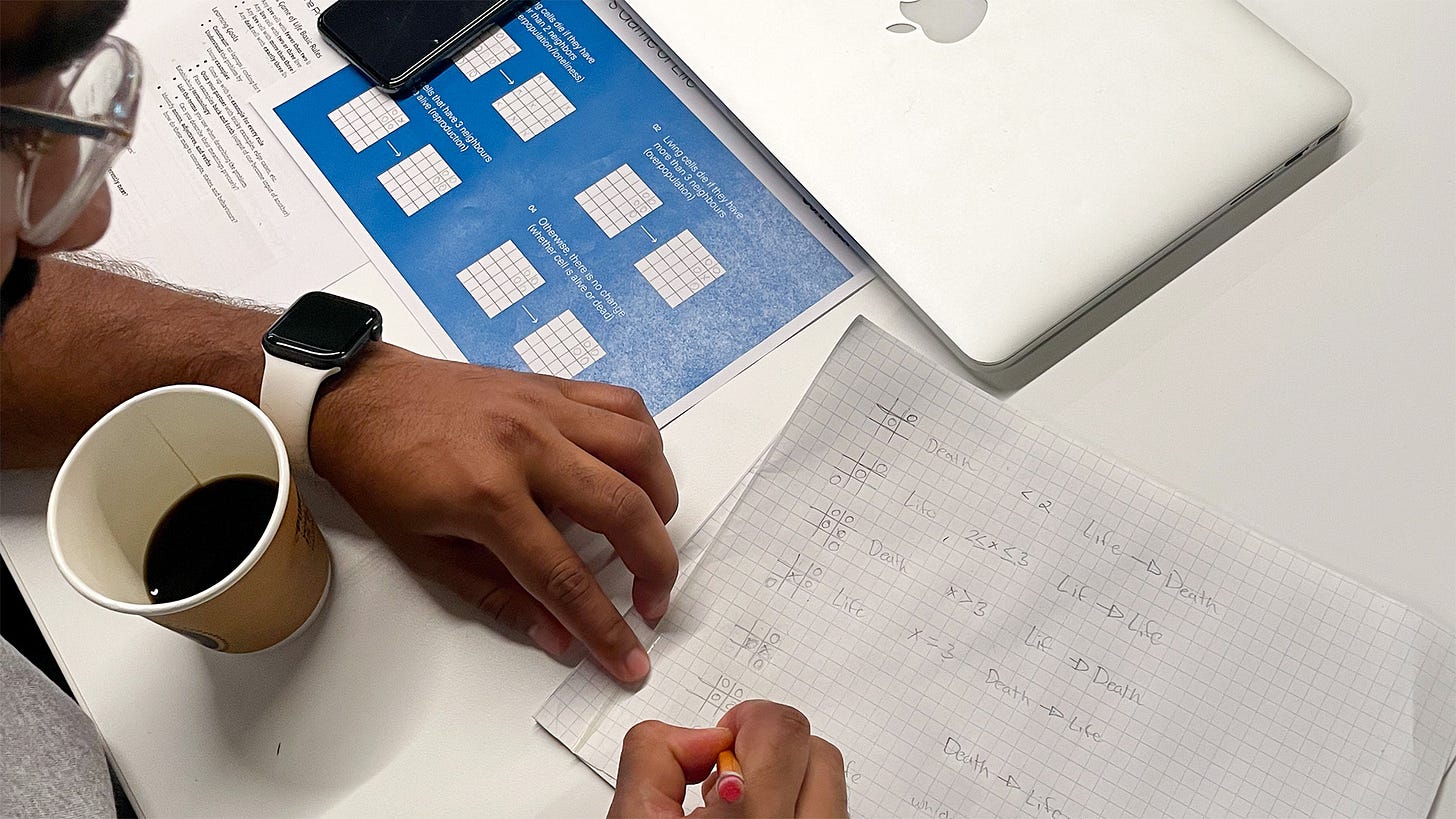 Close-up of coderetreat participant working through the four rules of Conway's Game of Life using a worksheet handout and grid paper.