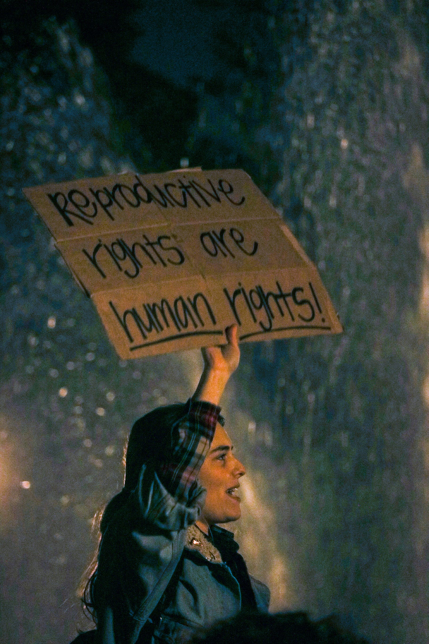 Woman holding up a cardboard sign that reads "Reproductive Rights Are Human Rights!" Woman holding up a cardboard sign that reads "Reproductive Rights Are Human Rights!"