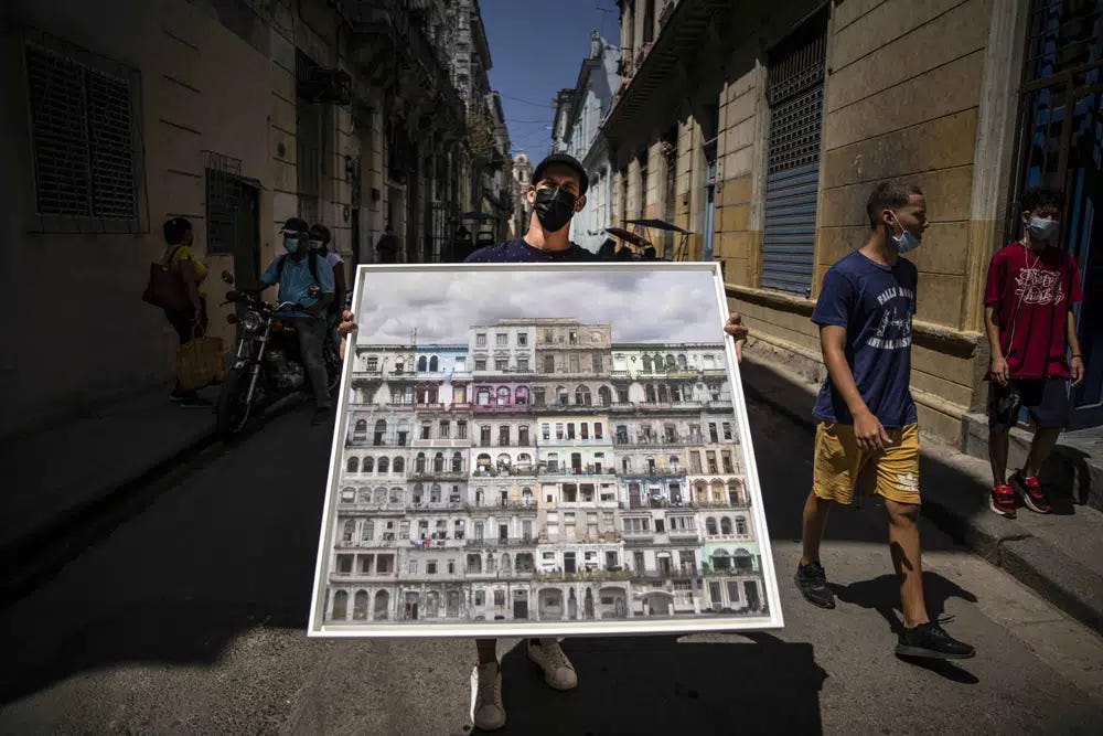 FILE - Photographer Gabriel Guerra Bianchini poses holding his photo collage titled “Hotel Habana 3/10” in Havana, Cuba, March 31, 2021. The photo is the first NFT, Non-Fungible Token, to be auctioned by an artist resident in Cuba, but in 2022, doors began to close for artists like him as key NFT trading platforms have gradually blocked Cuban artists on and off the island from their platforms. (AP Photo/Ramon Espinosa, File)