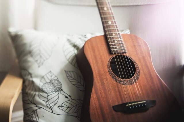 brown guitar on white pillow