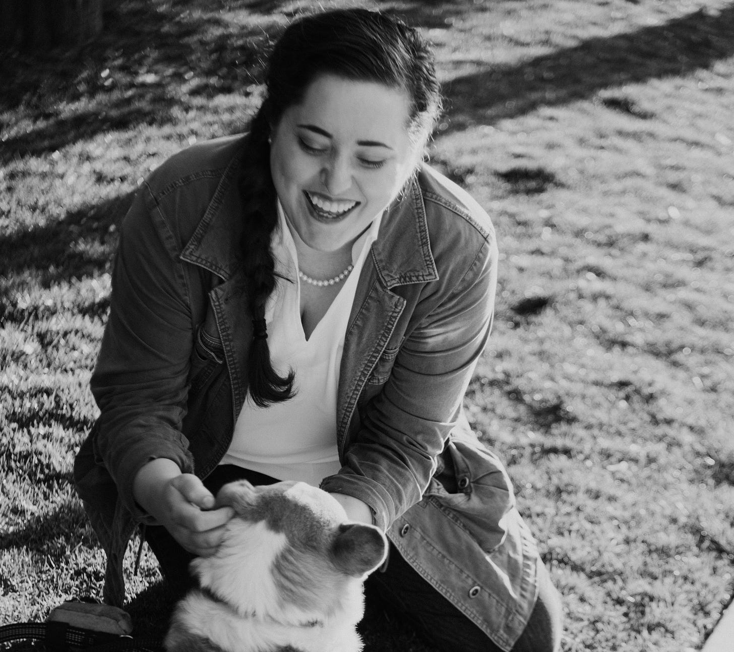 Black and white photo of woman smiling and petting a dog.