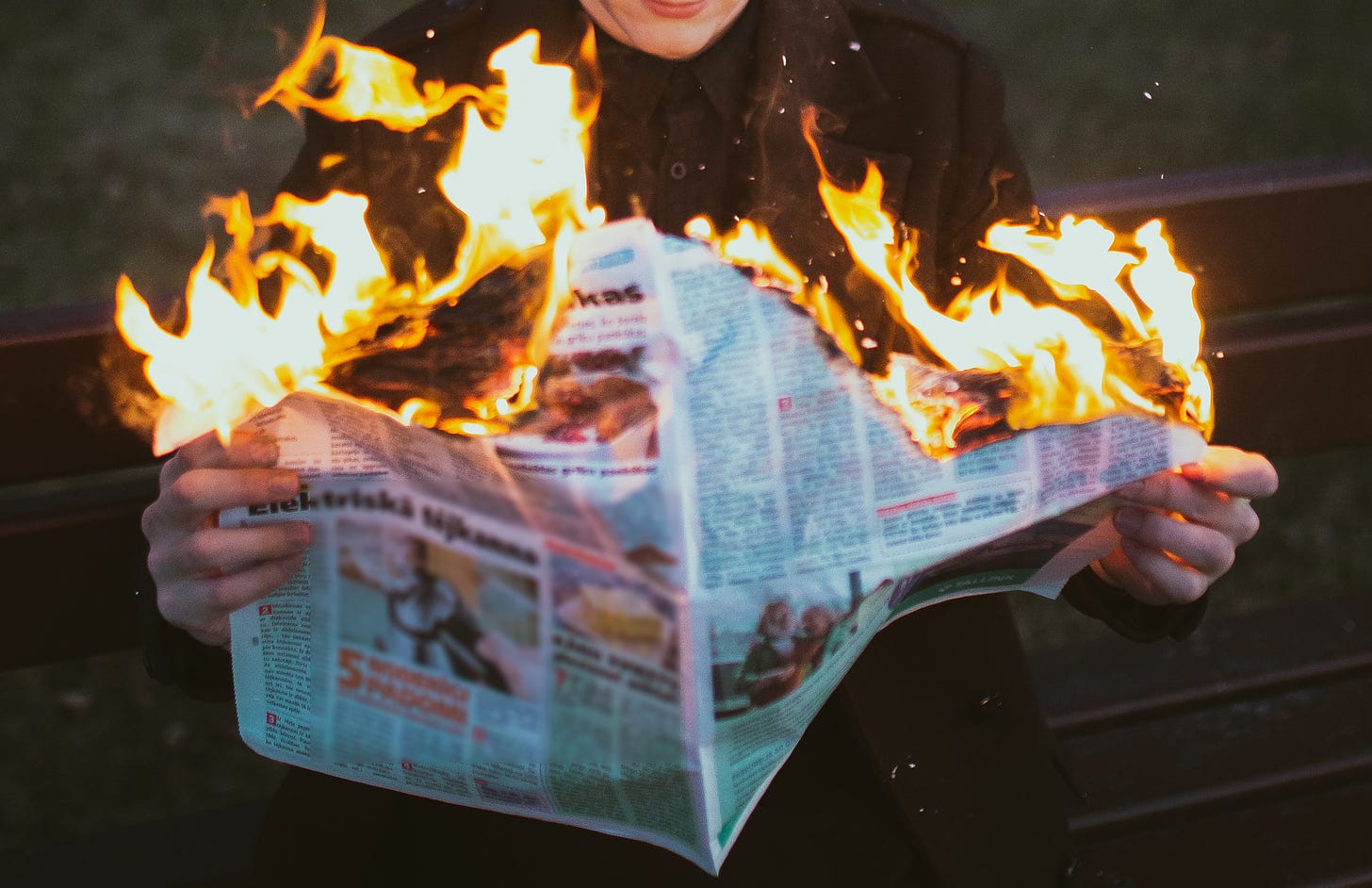 Photo of a guy reading a burning newspaper by Elvis Bekmanis from unsplash.com