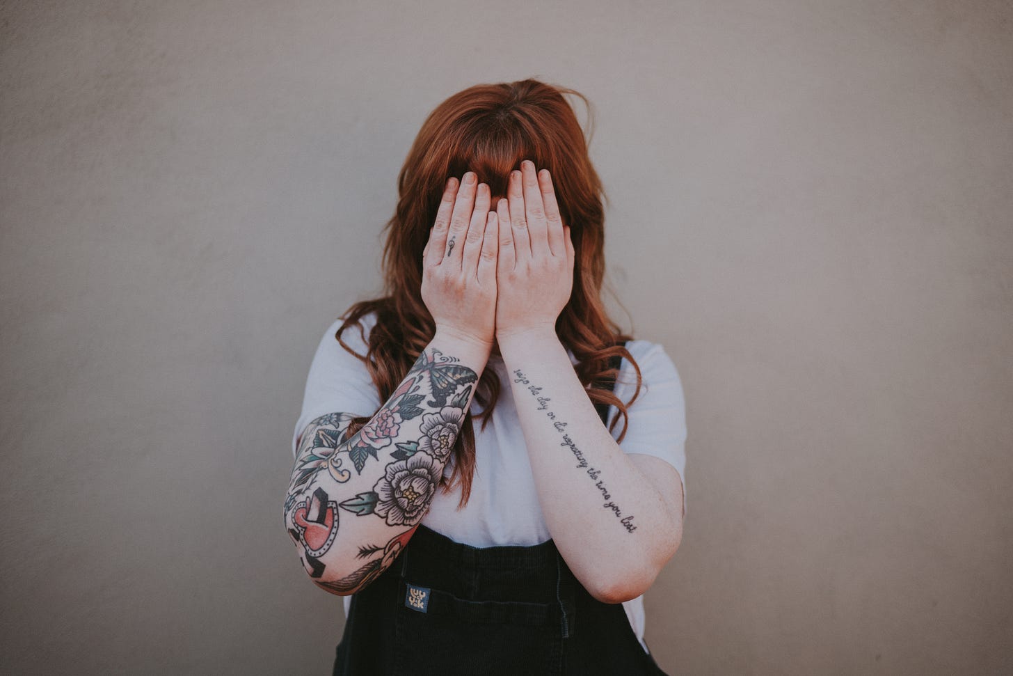 woman covering her face in front of wall photo