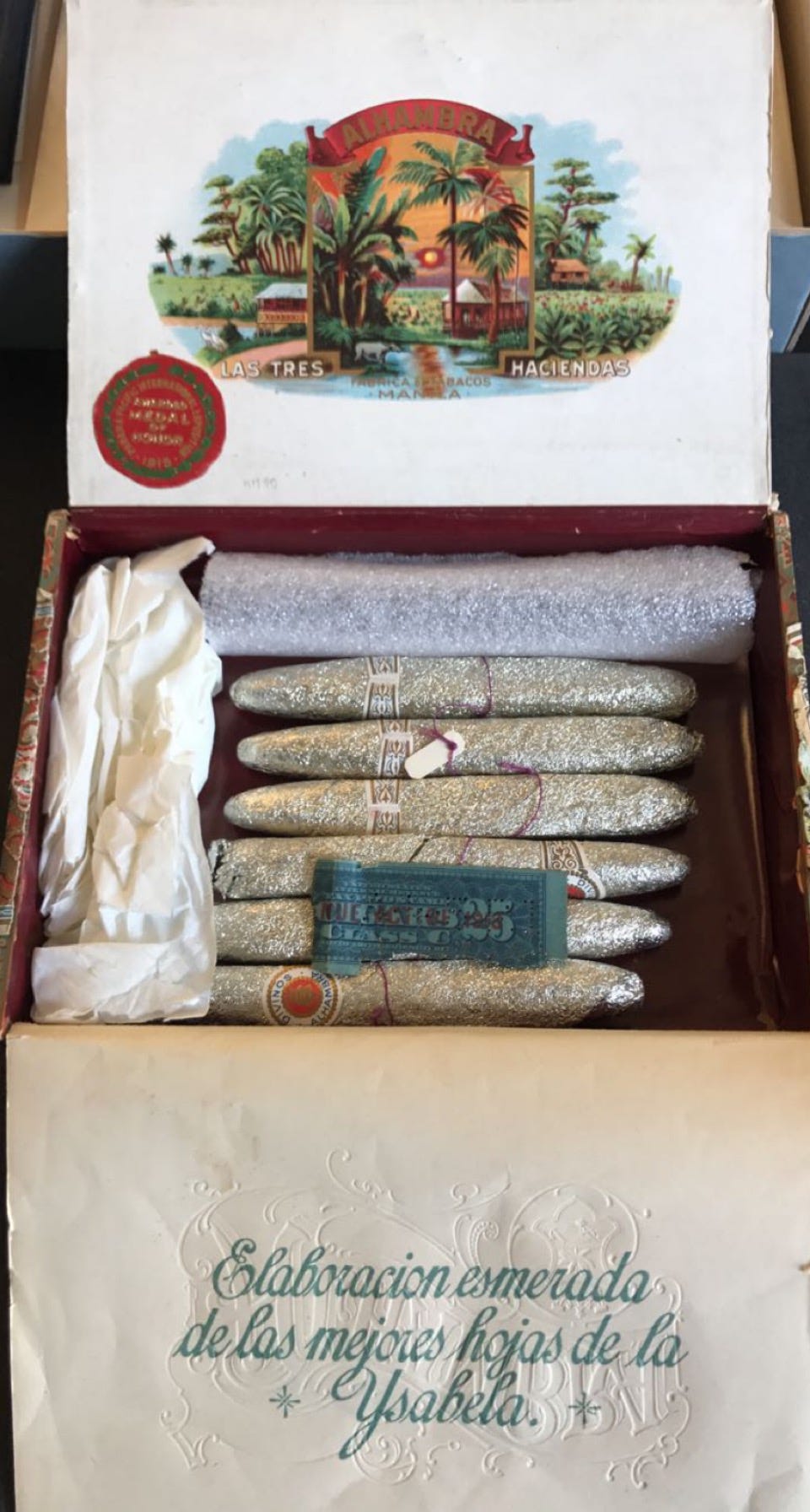 Image of cigar box opened to show six silver-wrapped cigars