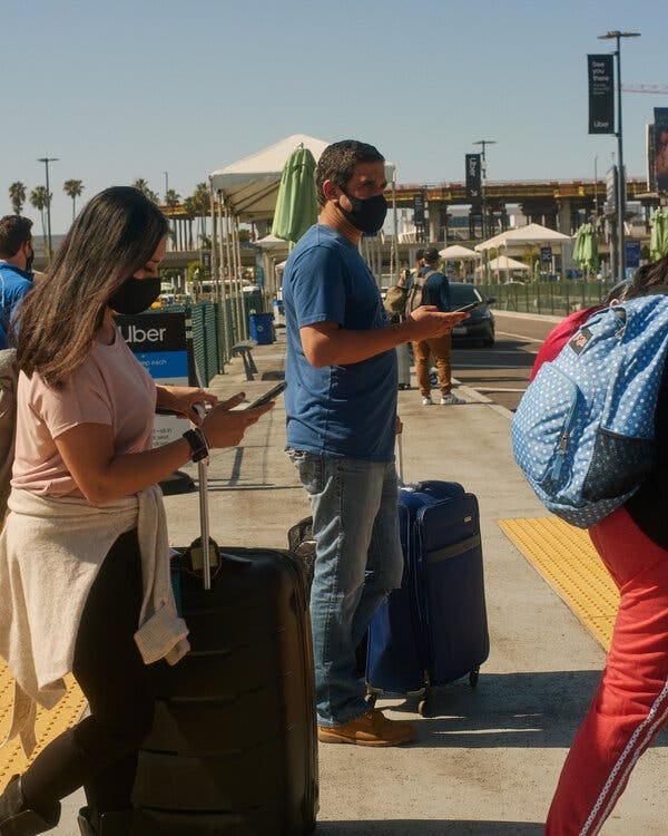 Travelers at Los Angeles International waiting for ride-hailing vehicles at the airport’s pickup lot last month.