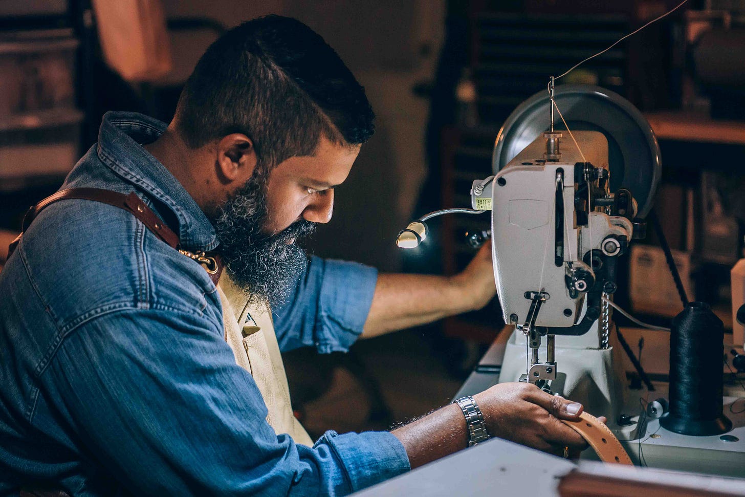 man sewing brown belt photo