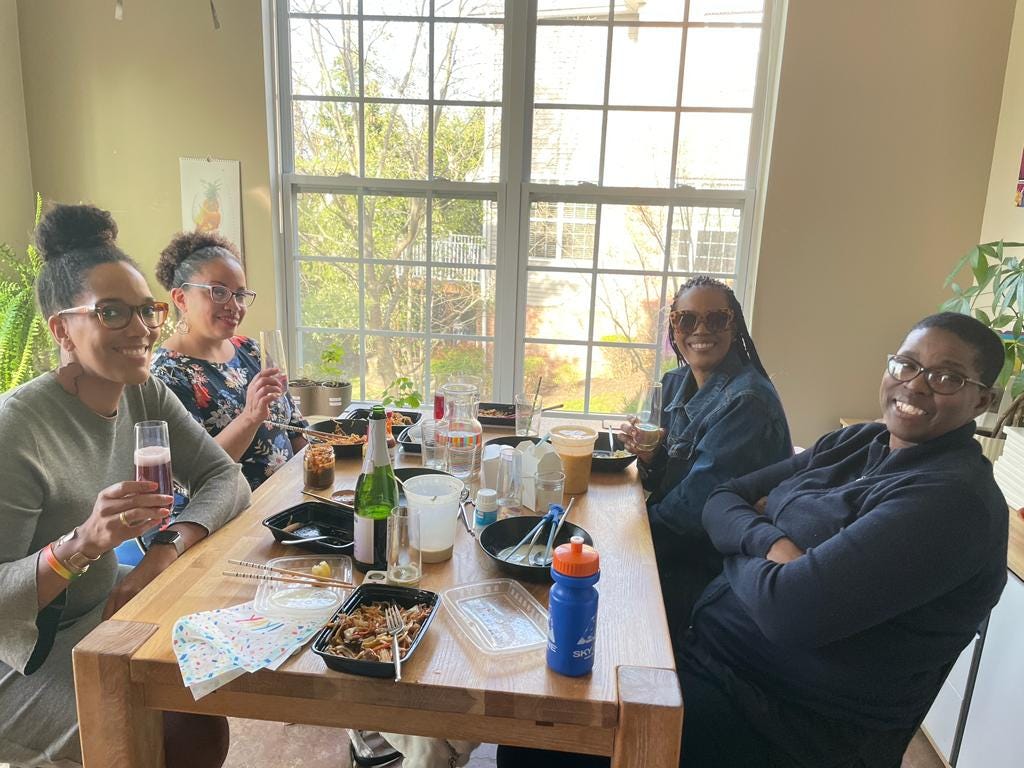 Left: Ellen Wagner and Ashanti Martin. Right: Sharon Hurley Hall and Lisa Hurley. The four Black women are seated around a table, holding glasses and toasting. They are smiling.
