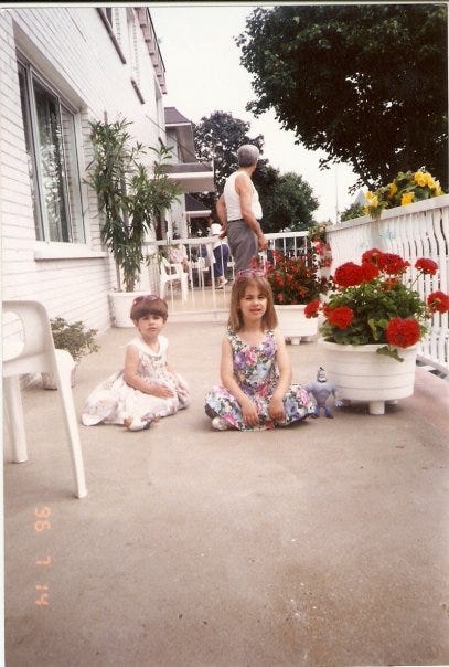 Cassandra and her sister sitting on the balcony of their grandparents' home in 1996. Their grandfather is in the bacgkground.