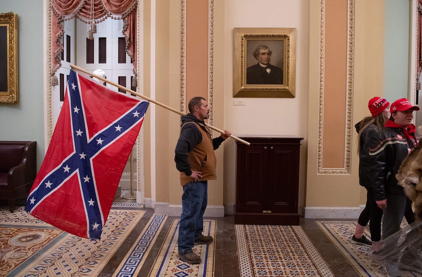 A Trump supporter carrying a Confederate flag, 2021