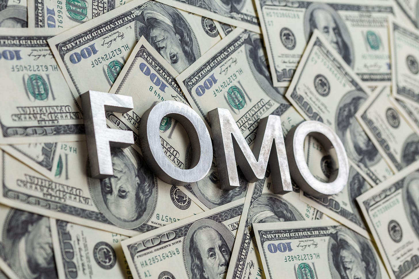 The word FOMO laid with aluminium letters on the US dollar banknotes background - with selective focus