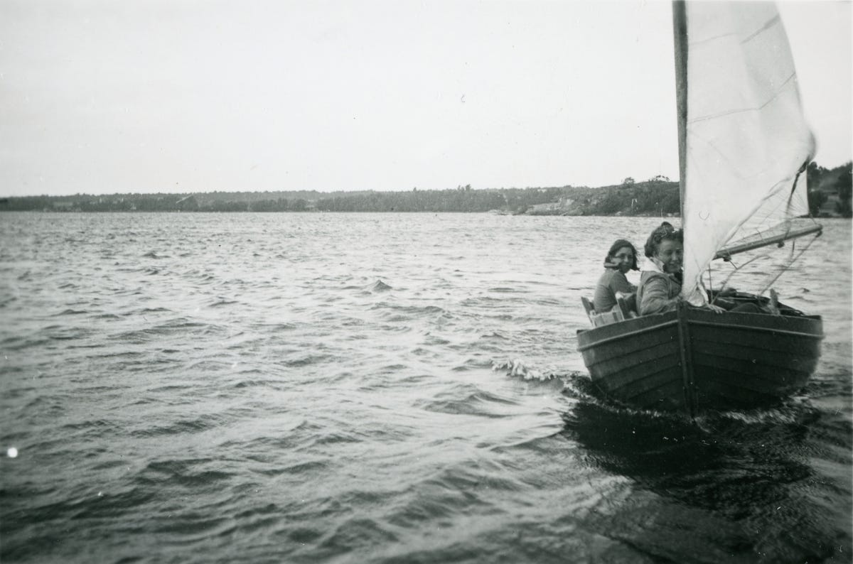 A black-and-white photograph depicting two young women on the seaside in a sailing boat.