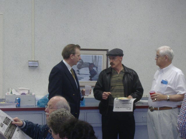 Joe Arminio discusses issues with one of his supporters. In the foreground is a gentleman reading one of his newspapers.