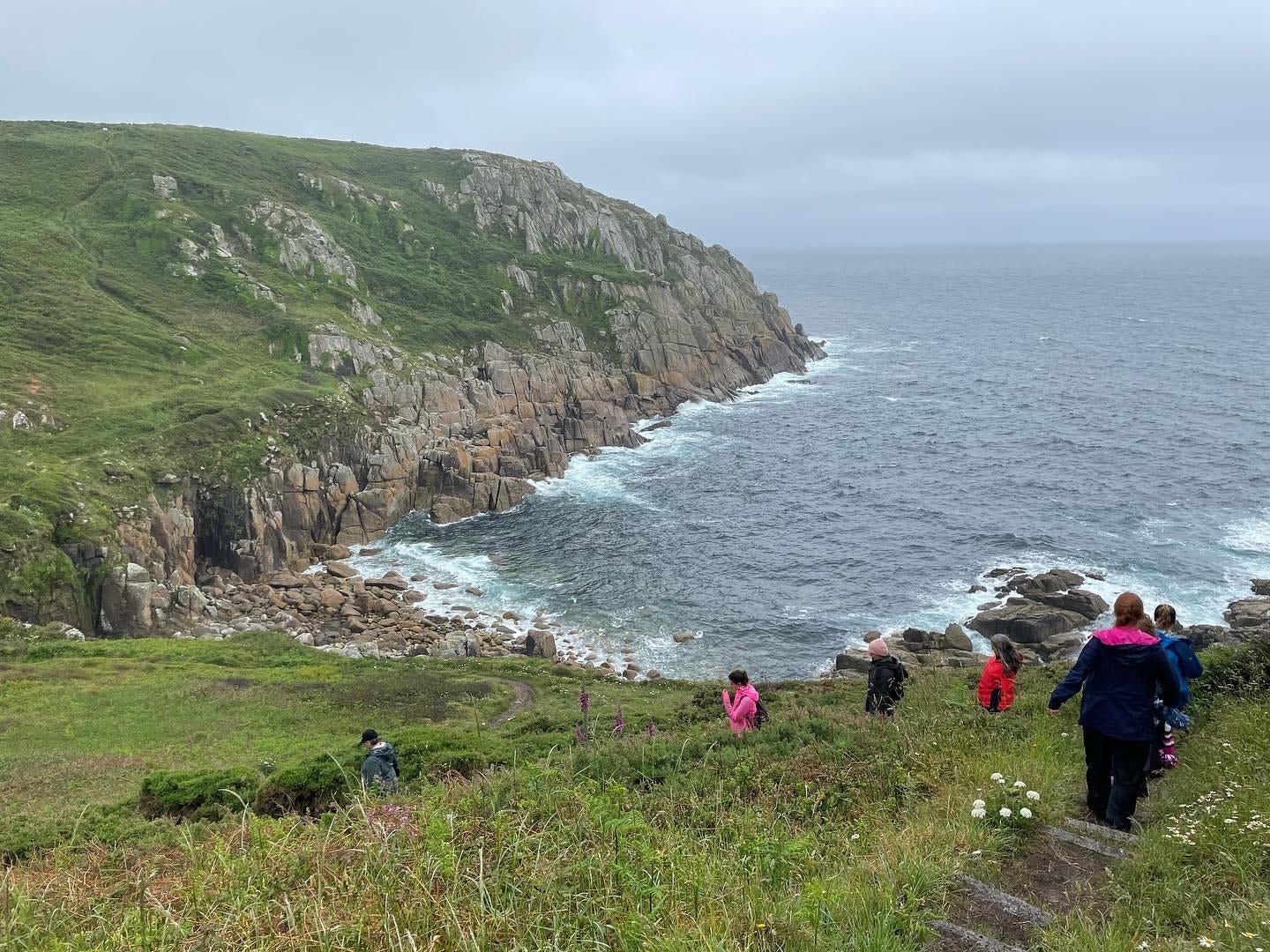 Colour photo of women walking single file along the south west coast path in cornwall
