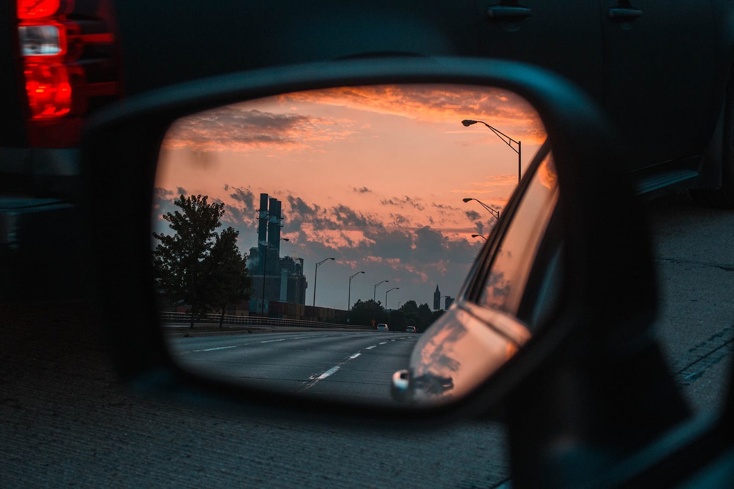 Photo of car side mirror reflecting the evening sky