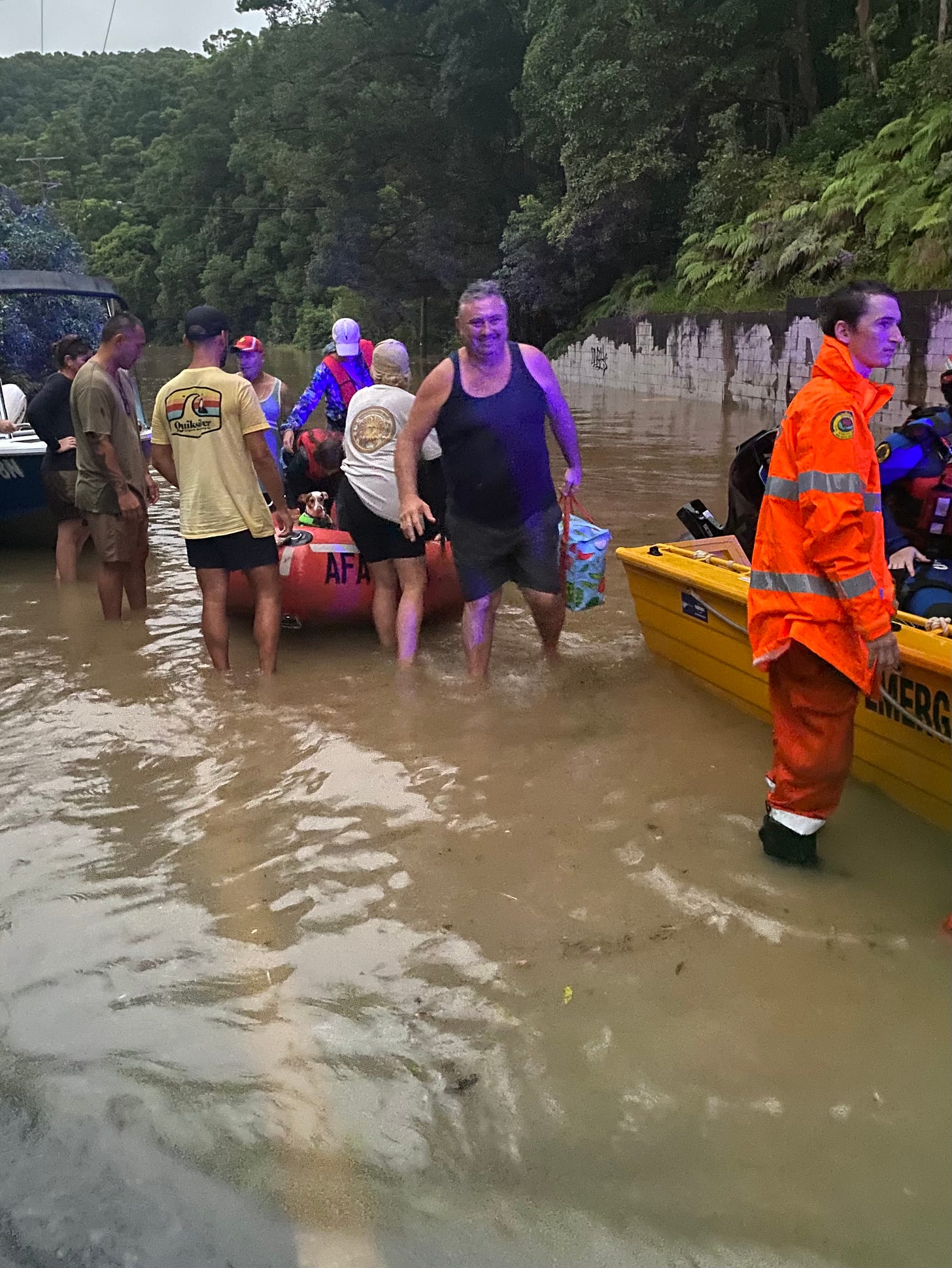 A man steps off a rescue dingy into flood water covering a road.