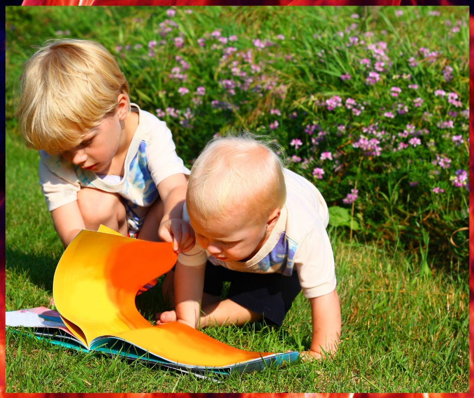 Two small innocent brothers reading a story book together in a garden.