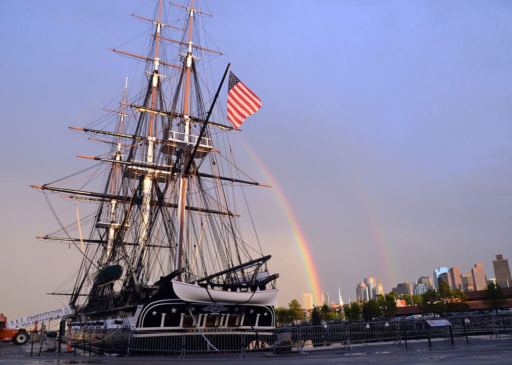 A photo of USS Constitution.  A double rainbow can be seen in the background.