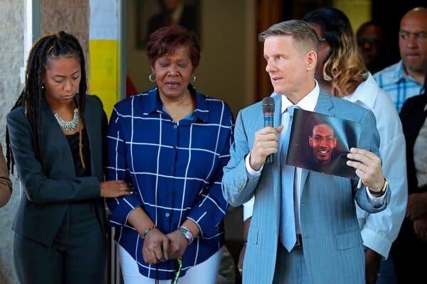 Bobby DiCello, right, a lawyer, displayed a photo of Jayland Walker, who was killed in a police shooting, as another lawyer, Paige White, left, comforted Mr. Walker’s mother, Pamela Walker, at a news conference on Thursday.