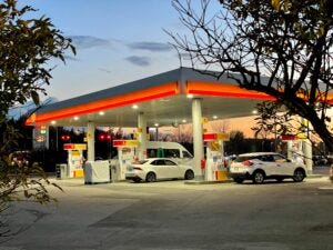 a gas station with trees around it and cars filling up