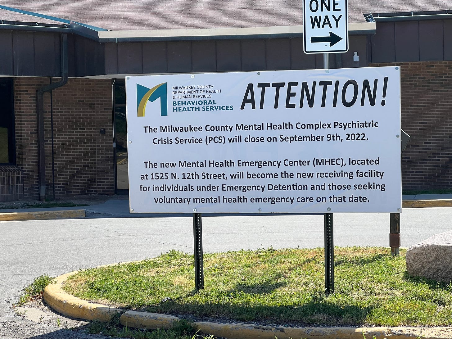 Image is of a sign in front of the Psychiatric Crisis Service (PCS) saying "Attention/The Milwaukee County Mental Health Complex Psychiatric Crisis Service will close on September 9th, 2022. The new Mental Health Emergency Center (MHEC), located at 1525 N. 12th. Street, will become the new receiving facility for individuals under Emergency Detention and those seeking voluntary mental health emergency care on that date."