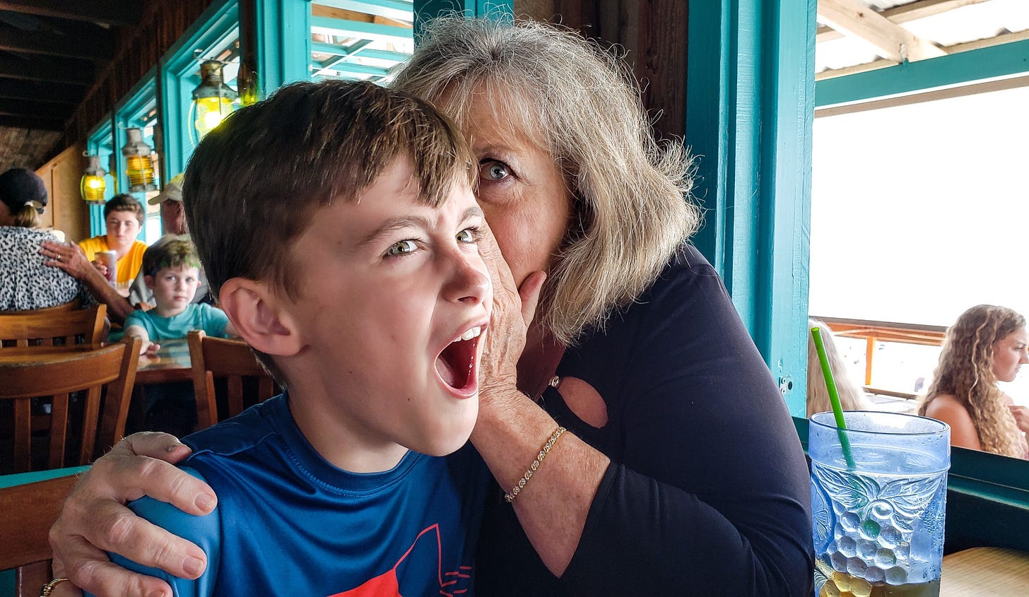 A grandmother clutches her grandchild and whispers in his ear. His face is one of shock.