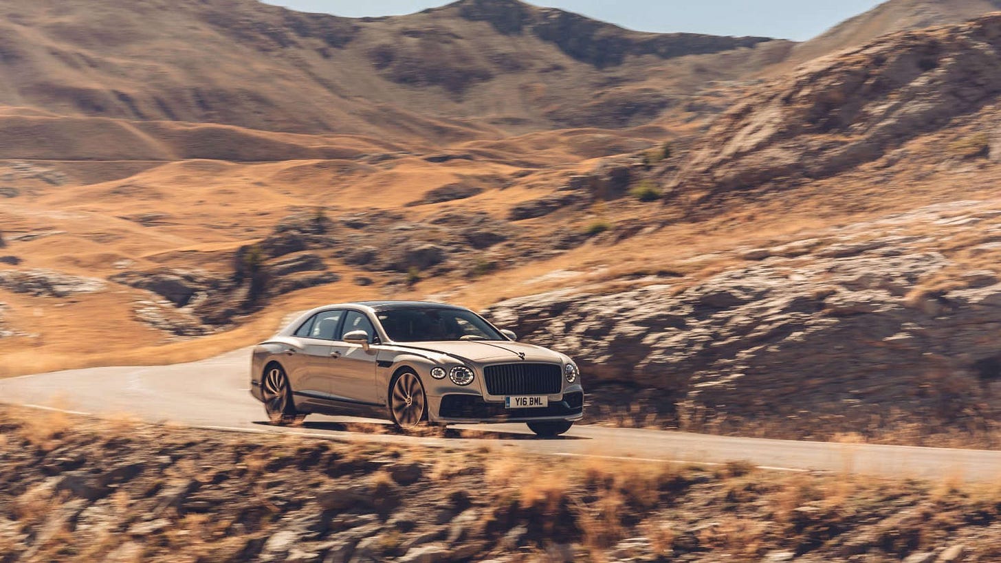 a car with a mountain in the background: Bentley Flying Spur