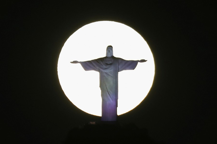 The moon appears behind an enormous statue of Christ.