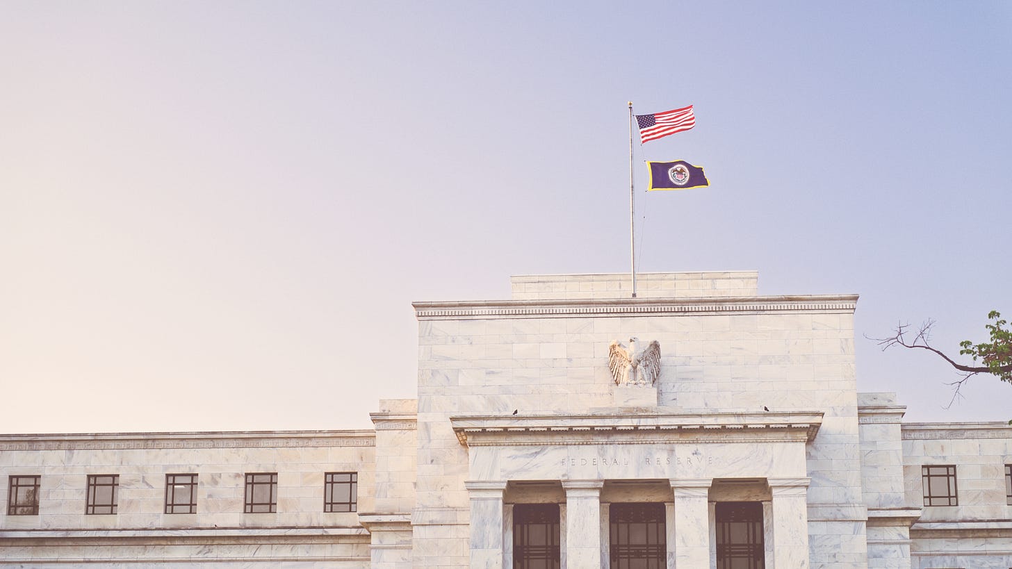 upper portion of federal reserve building with the united states flag and federal reserve bank flag