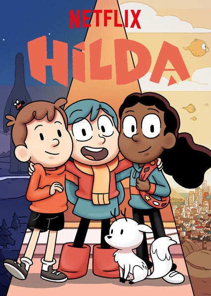 Image is a show poster for “Hilda,” with the Netflix logo at the top and the title of the show below it. Three human figures are in the center of the picture; left to right they are a light-skinned boy with brown hair, an orange sweatshirt, and black shorts, a light-skinned girl with blue hair wearing an orange scarf, red sweater, and blue skirt with red books, and a dark-skinned girl with dark hair wearing a red sash, a blue hoodie with an orange stripe, and black pants. In front of the trio, offset to the right, there is a small white dog-like creature with antlers.