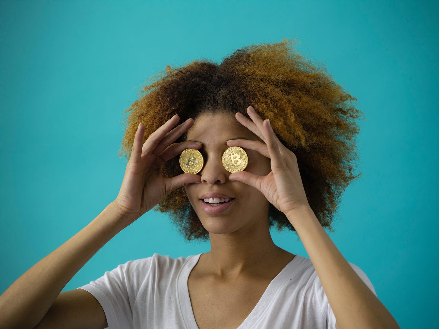 A woman with two physical Bitcoin coins over her eyes