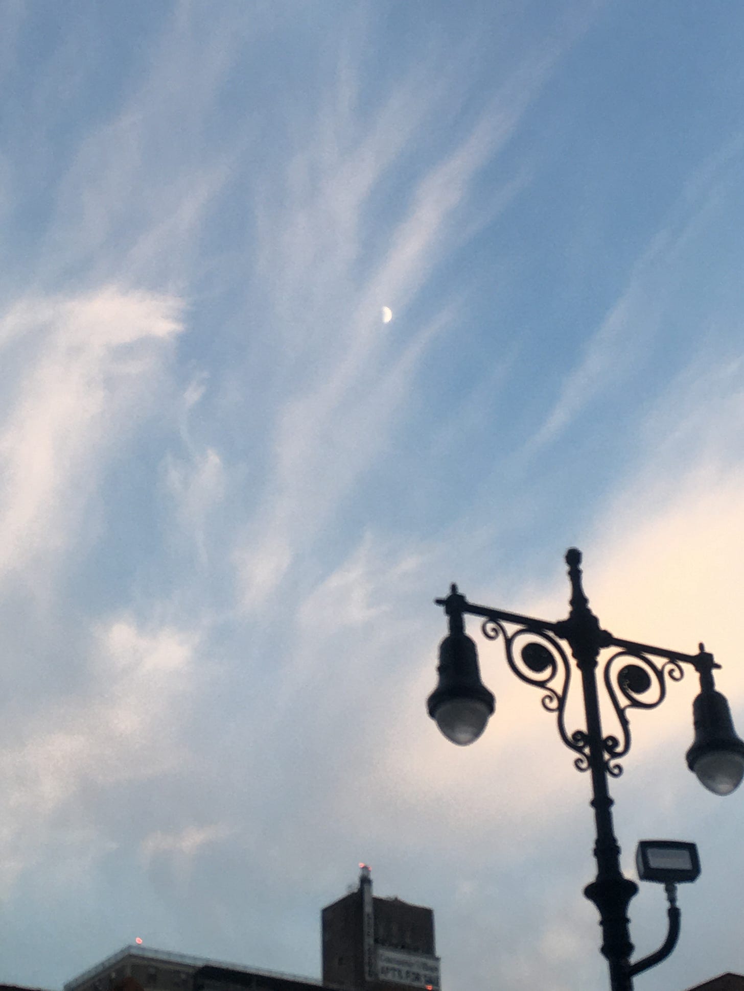 photo by me: first quarter moon on dec 21 with wispy clouds above a lampost and top of a building