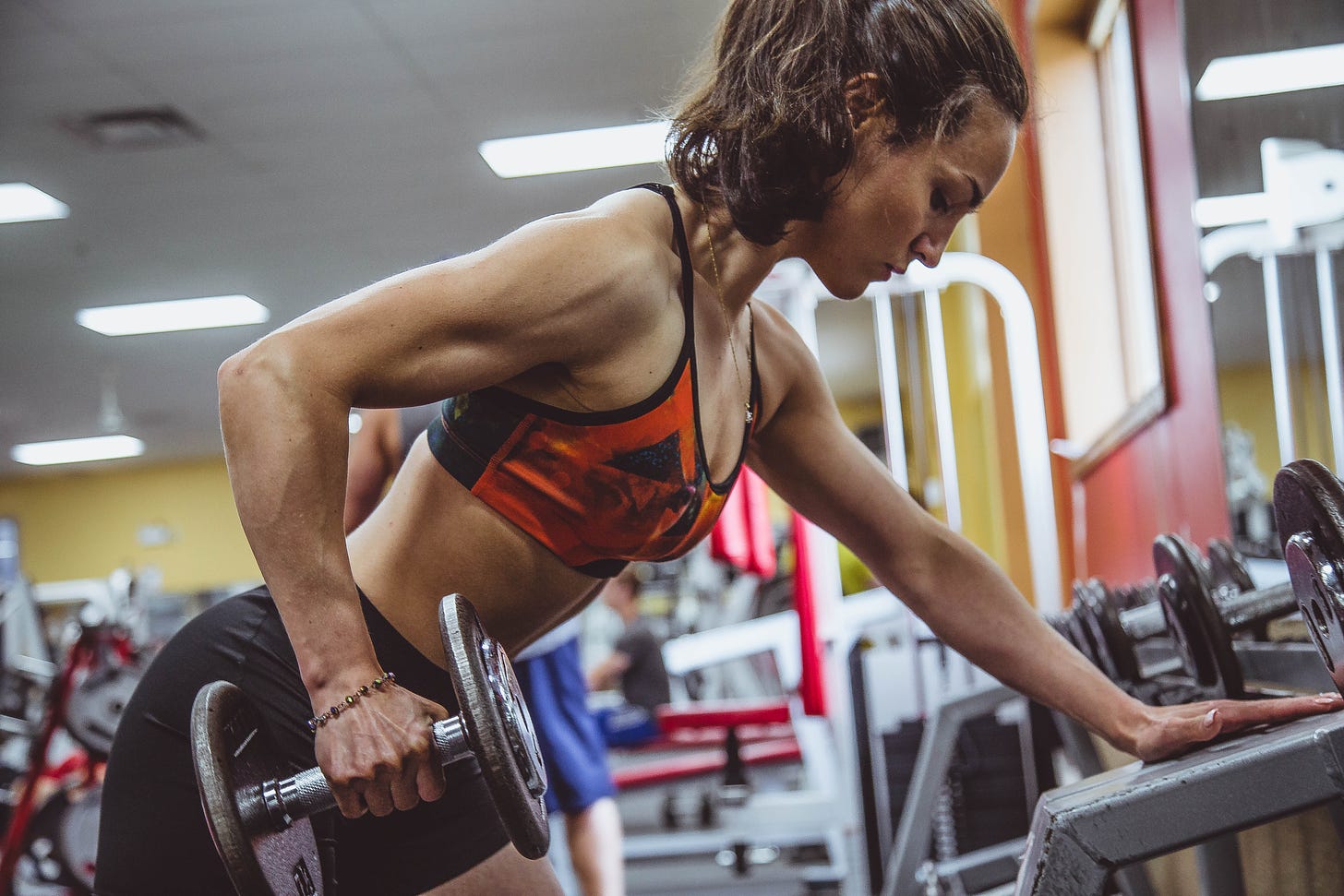 Woman lifting weights at the gym via unsplash