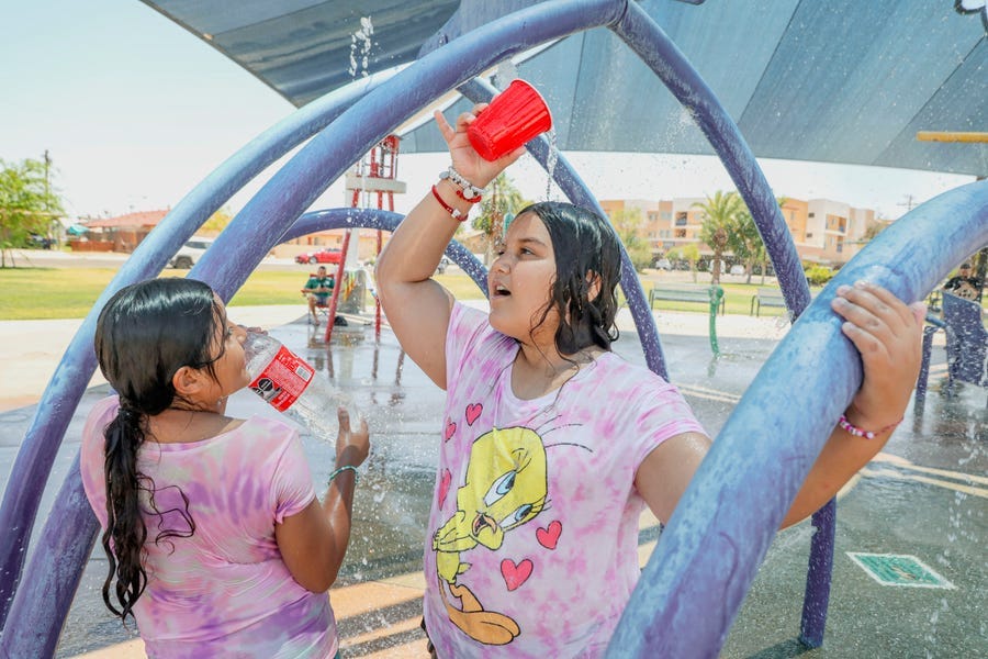 Veronica and Maria Sanchez play at a water park as the temperature reaches 115 degrees on June 12, 2022 in Imperial, California.