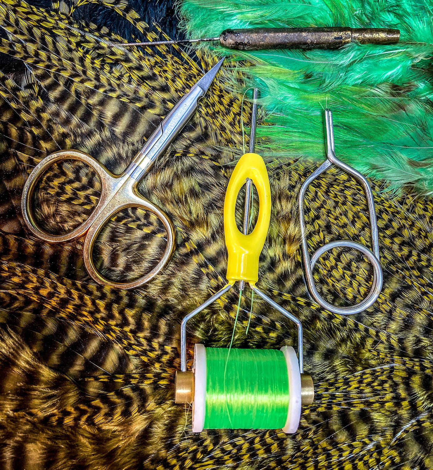 Basic tying tools (counter-clockwise from top, left): scissors, bobbin, hackle pliers and (well-used) bodkin. [Photo: Dean Shadley]