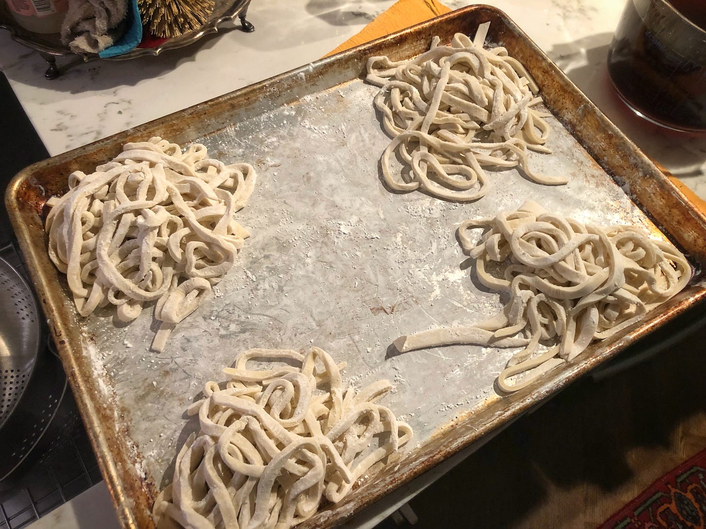 A metal sheet tray with four nests of noodles heavily dusted in corn starch