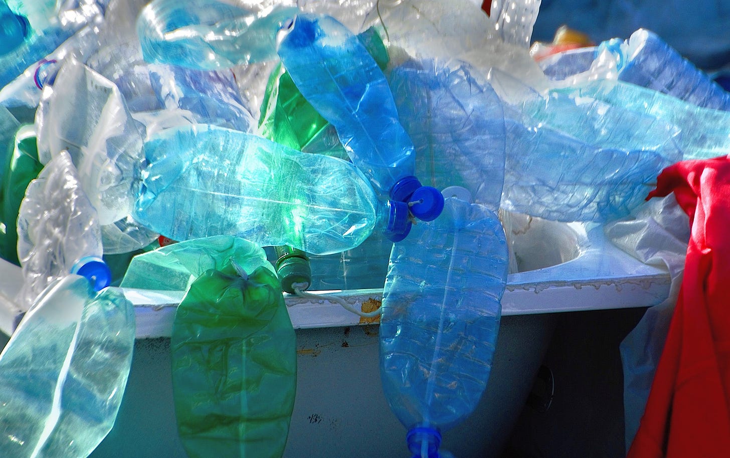 Plastic bottles and bags in a dumpster.