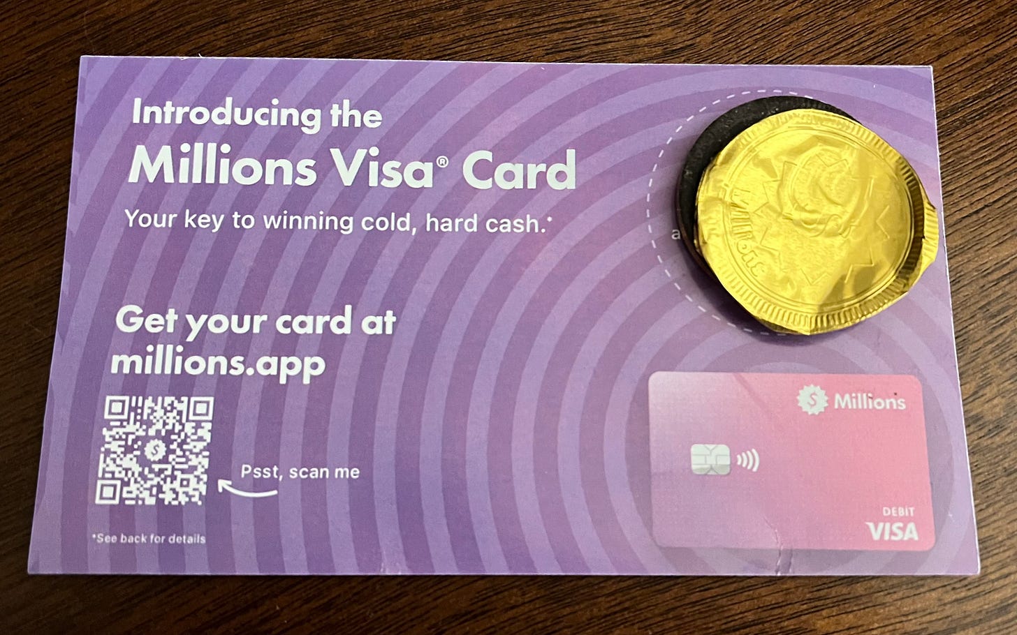 A chocolate coin attached to an advertisement for the Millions Visa Card.