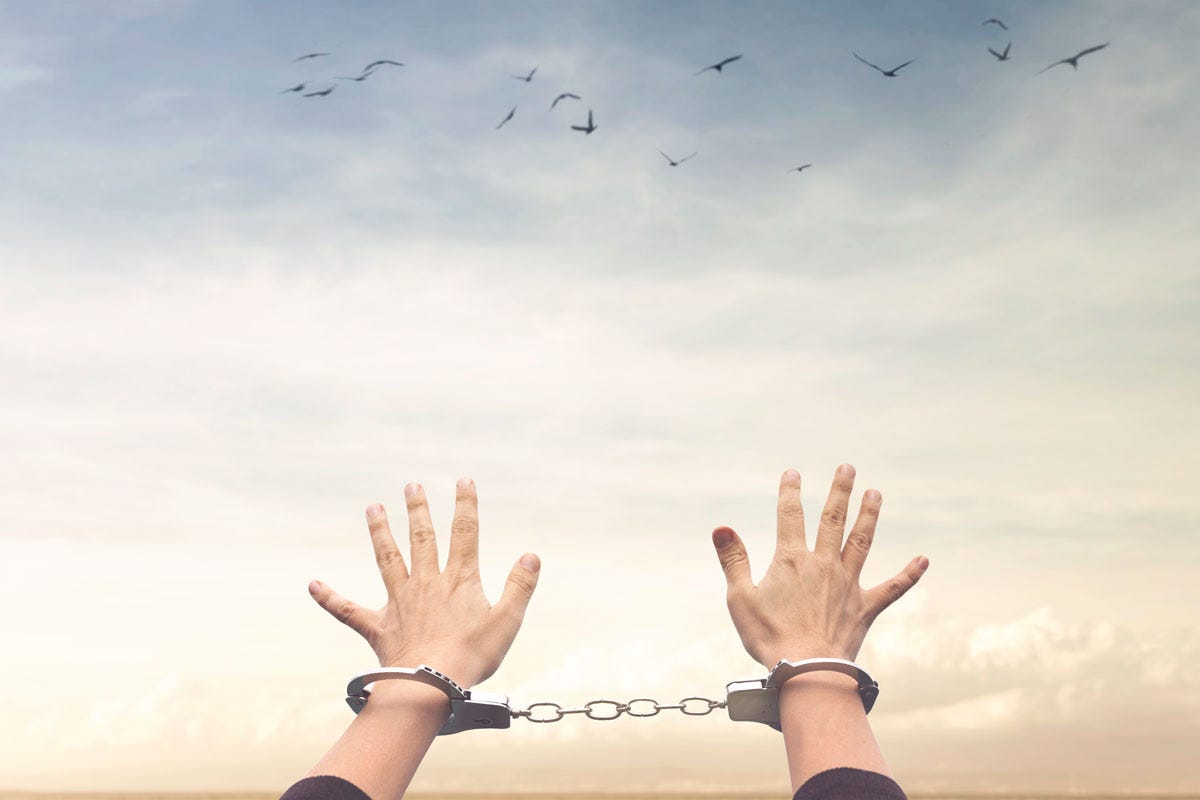 Handcuffed Person Reaching Toward Sky Filled with Birds