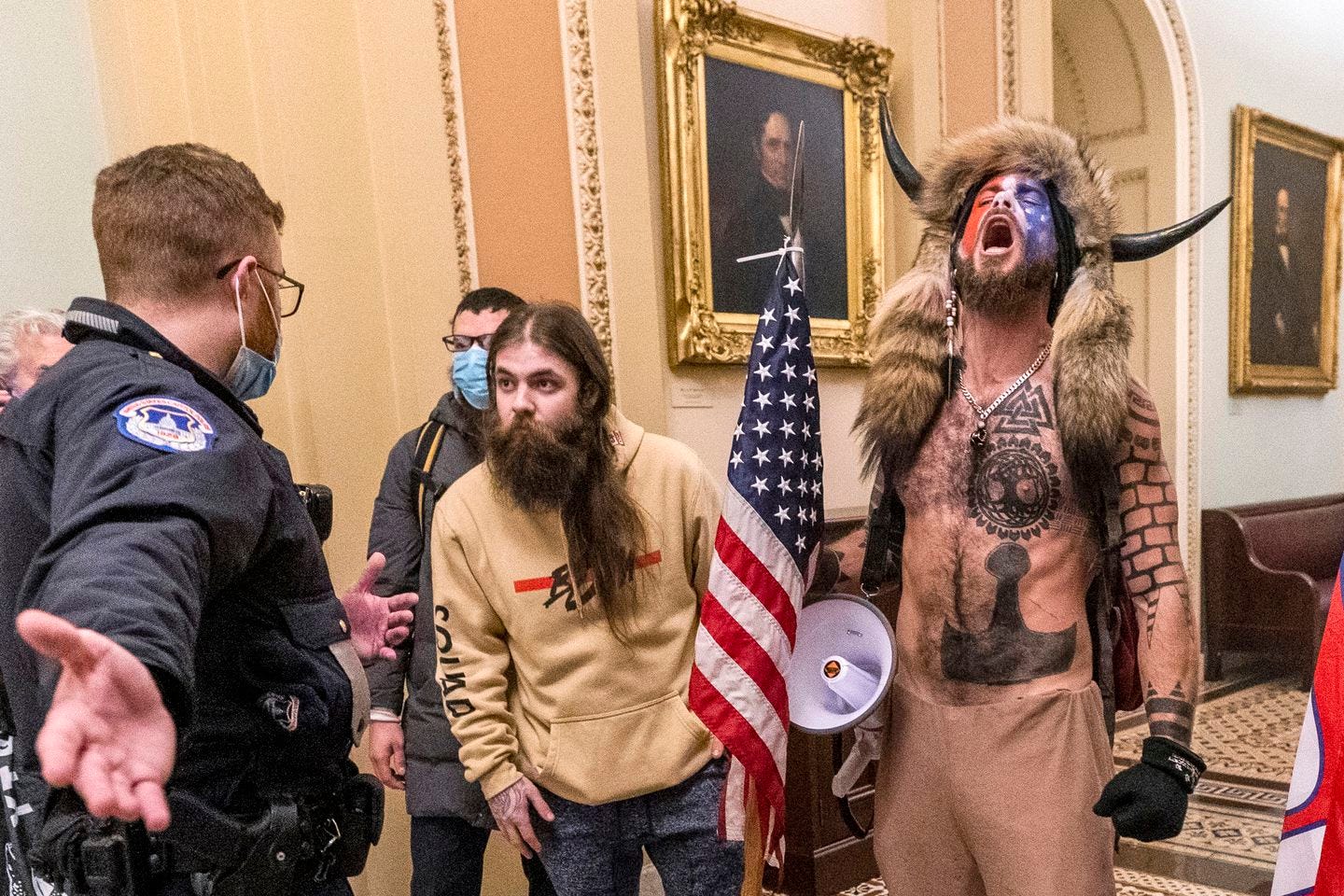 Jacob Chansley, right with fur hat, during the Jan. 6 Capitol riot in Washington. Chansley pleaded guilty Friday to a felony obstruction charge. He carried a flagpole topped with a spear into the insurrection, yelled into a bullhorn as officers tried to control the crowd, posed for photos on the Senate dais, and wrote a note to then-Vice President Mike Pence that prosecutors have said was threatening.